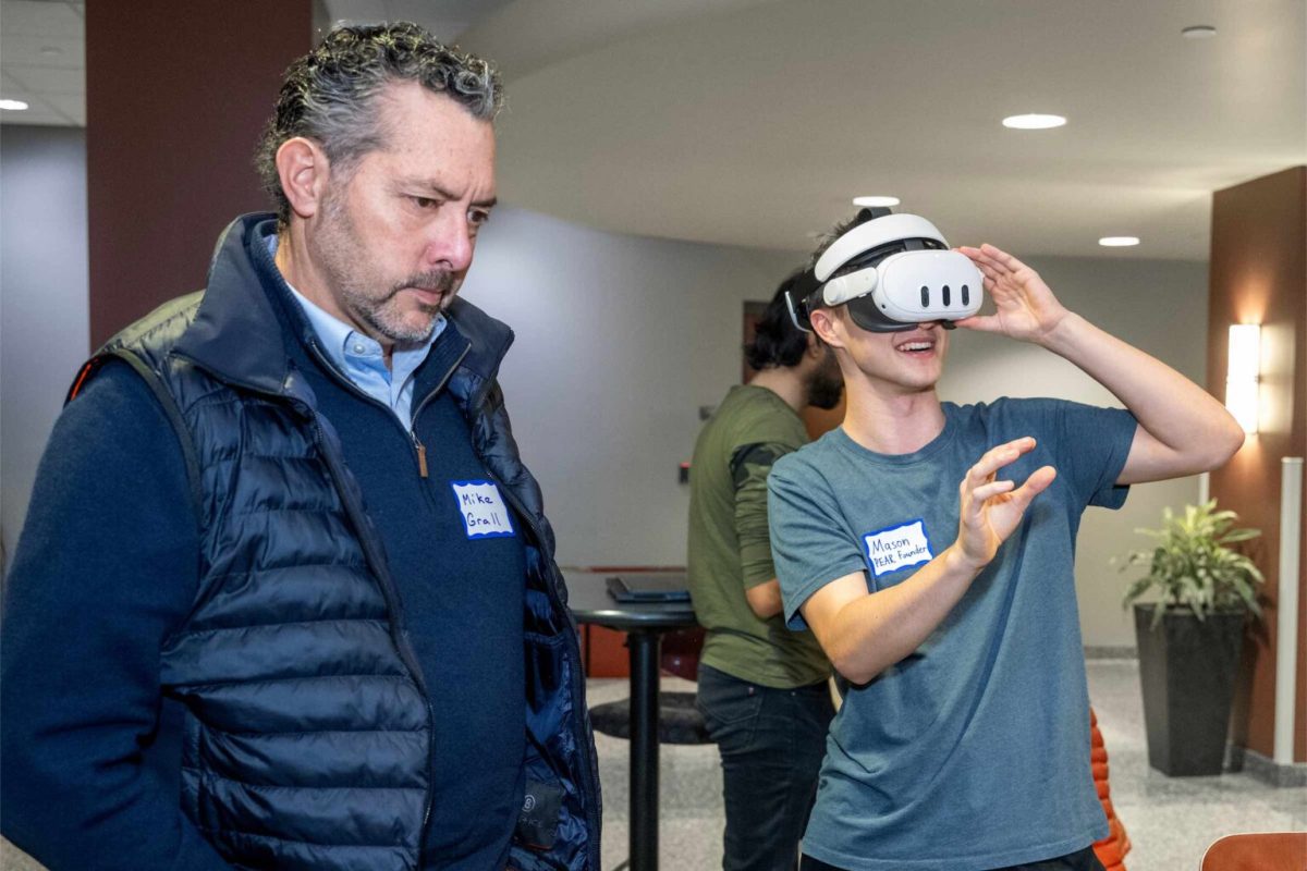 Mike Grall, CEO with Fulcrum Solutions watches a demo of a Quest headset with UW-Madison student Mason Baloun.